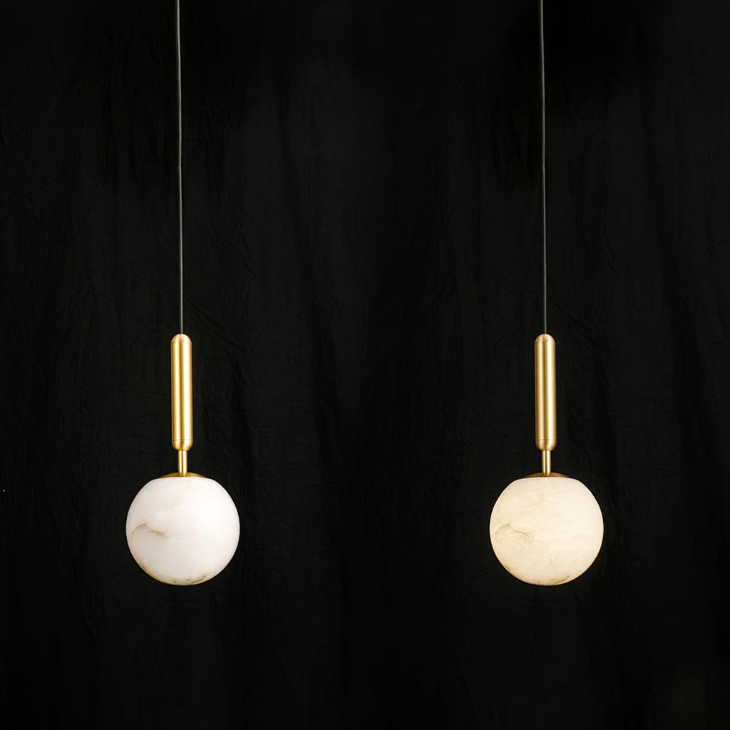 Close-up against black of the brushed brass stem meeting the top of the alabaster globe.