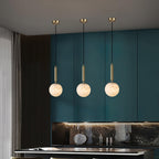The pendant on white with its brass stem, alabaster globe unlit and softly veined.