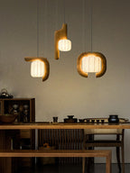 Above a kitchen counter lined with jars and teapots, three shades of this dark wood Clérachic fixture glow warm.