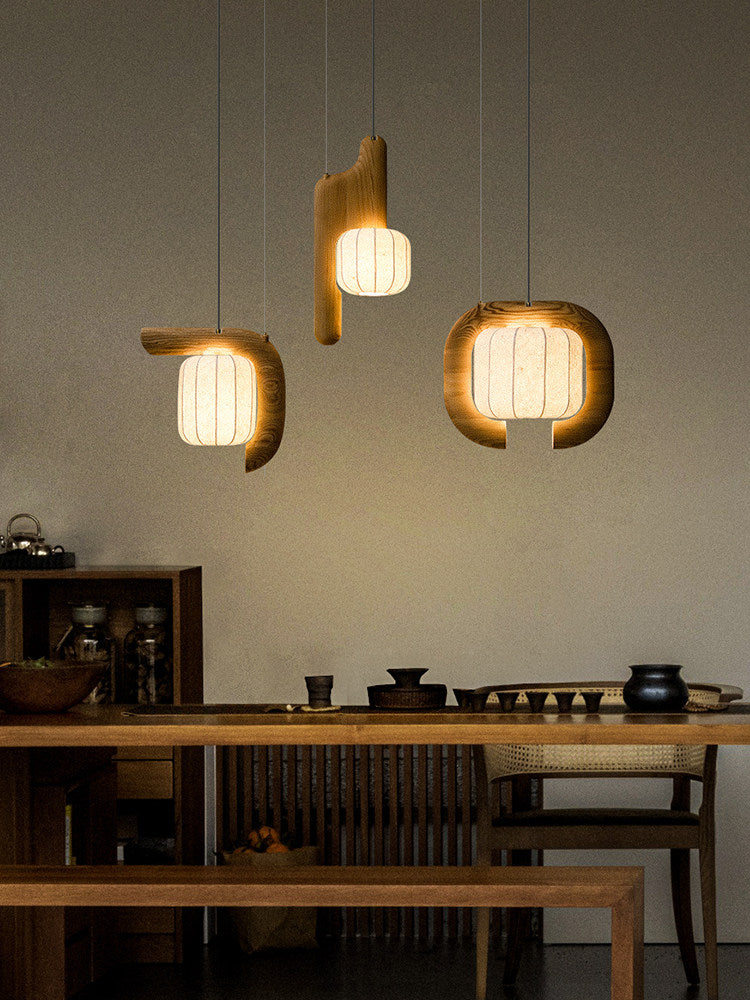 Above a kitchen counter lined with jars and teapots, three shades of this dark wood Clérachic fixture glow warm.