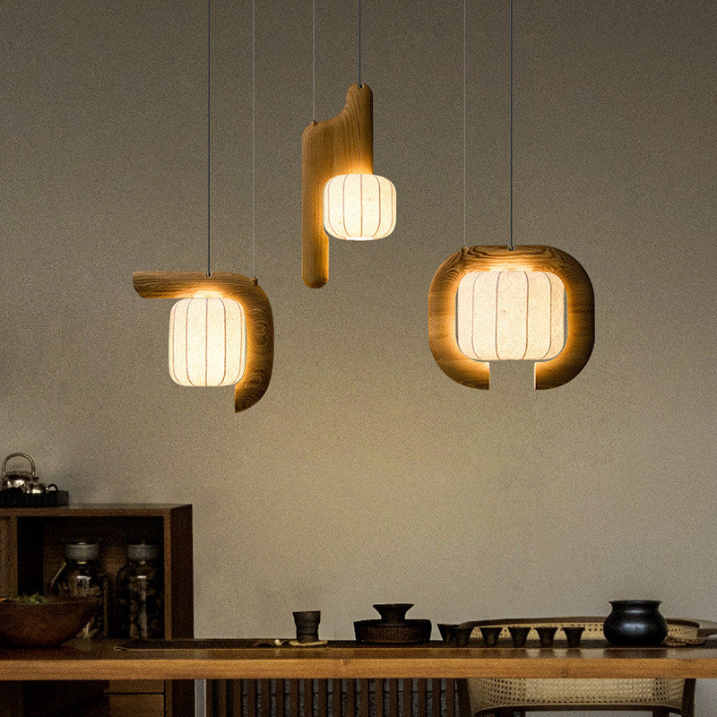 Three shades of this dark wood Clérachic fixture glow above a wood counter set with small jars and bowls.