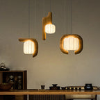 Three shades of this dark wood Clérachic fixture glow above a wood counter set with small jars and bowls.