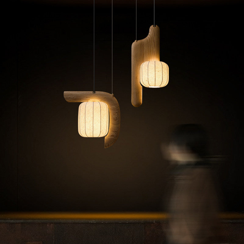 In a dim room, two shades of this dark-finished Clérachic fixture glow above blurred figures walking below.