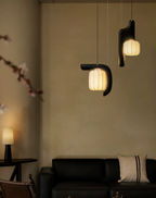 Beside a leather sofa and a small table lamp, two shades of this black Clérachic fixture glow softly overhead.