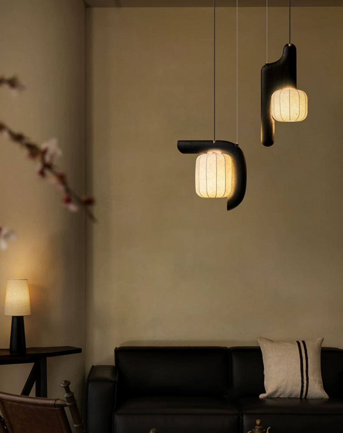Beside a leather sofa and a small table lamp, two shades of this black Clérachic fixture glow softly overhead.