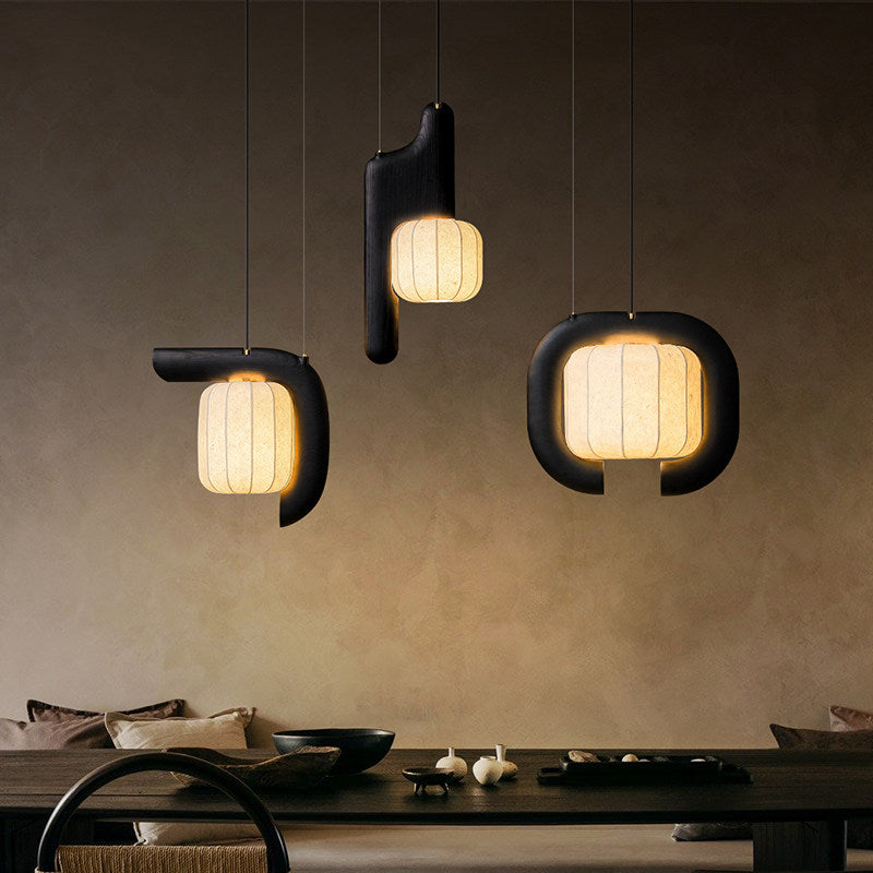 Three shades of this black Clérachic fixture, vertical, bent and closed-loop, glow warm above a dark dining table.