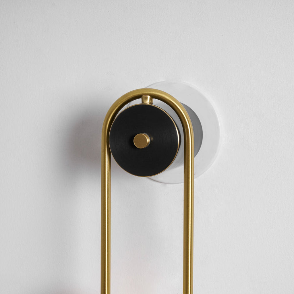 Curved brass wall light with two glowing white glass shades