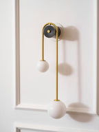 Curved brass wall light glowing warmly with two glass shades