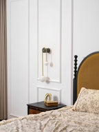 White glass shades lit on a curved brass arm wall light