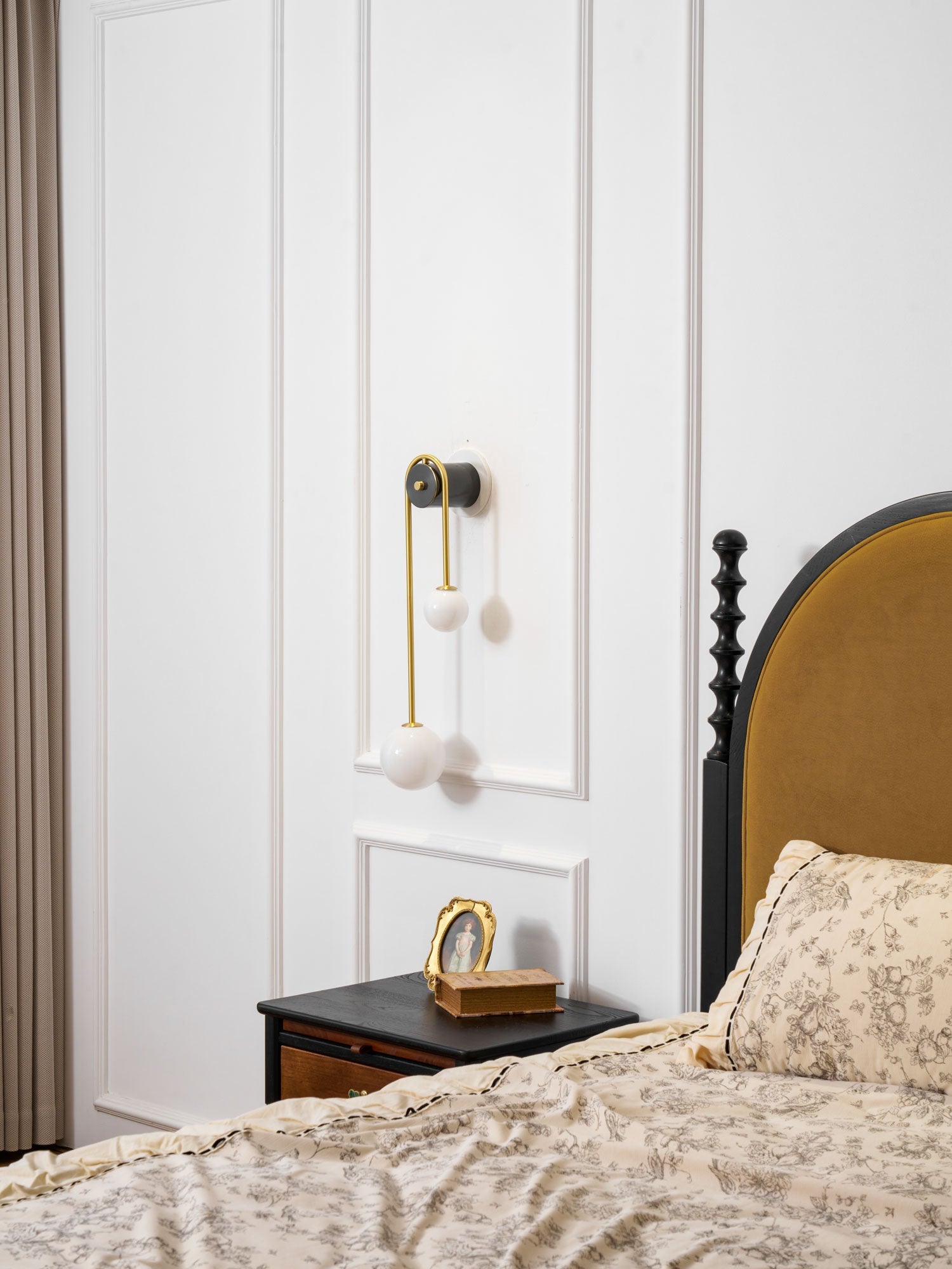 White glass shades lit on a curved brass arm wall light