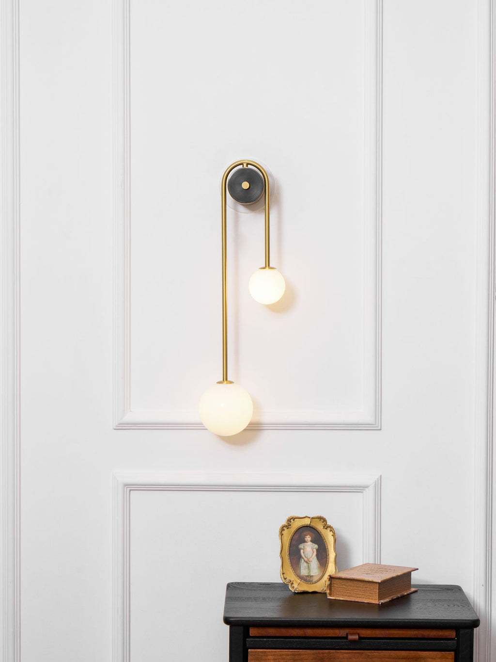 Curved brass wall light with offset shades in a hallway setting