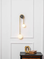 Curved brass wall light with offset shades in a hallway setting