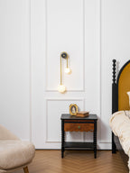 Brass arc wall light shown glowing against a dark wall