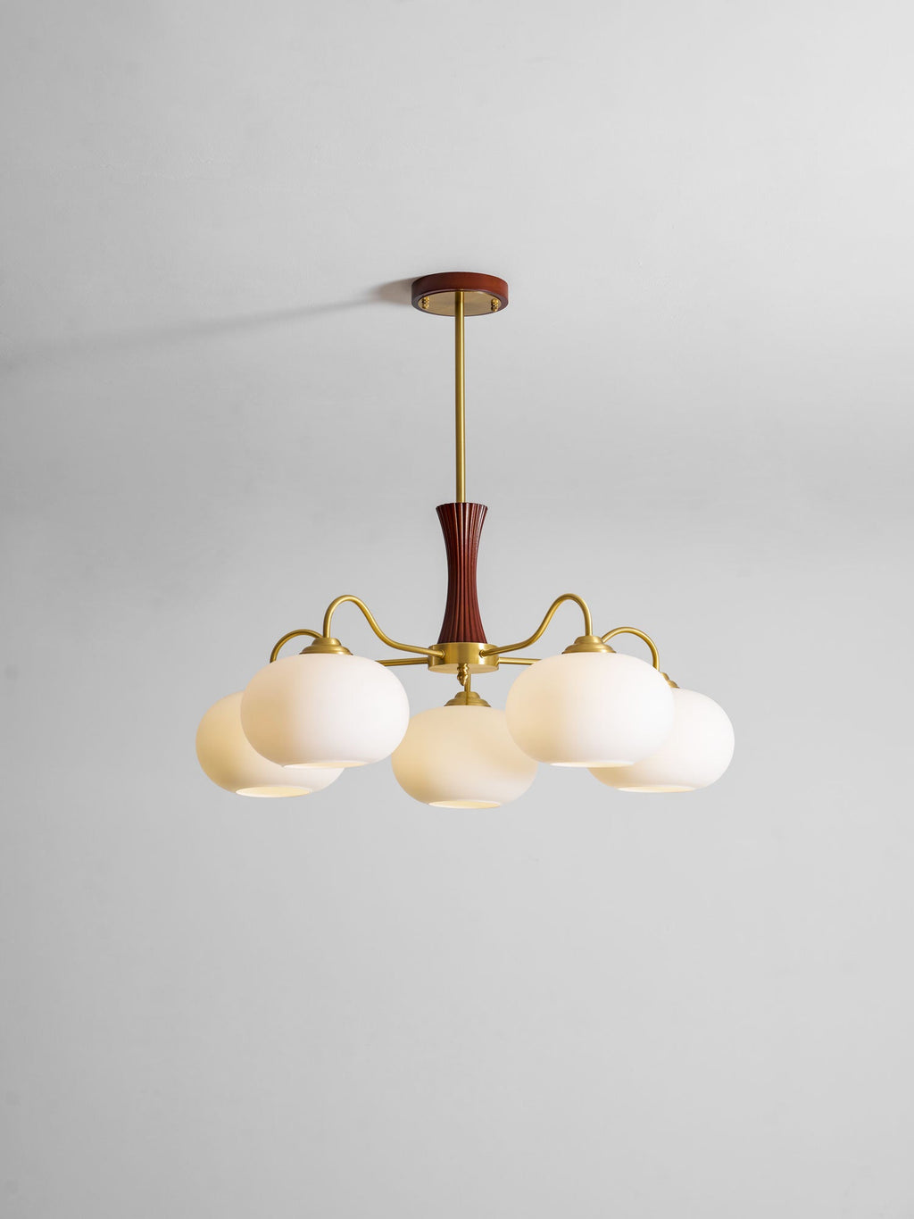 Persimmon chandelier detail with warm brass and glass shades