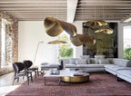 Clérachic hammered brass shades hang in a rustic living room with stone walls and a grey sofa.