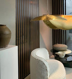 Unlit, this large Clérachic hammered brass shade hangs near a terracotta vase and a slatted wood wall.