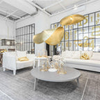 Two lit Clérachic pendants hang in a white showroom with a glass partition and a sofa.