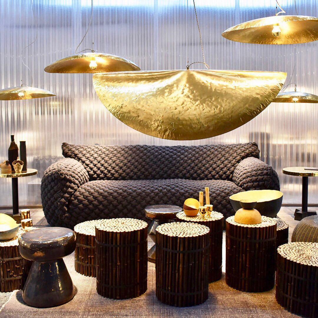 Several Clérachic pendants hang in a showroom lined with beige armchairs and a glass wall.