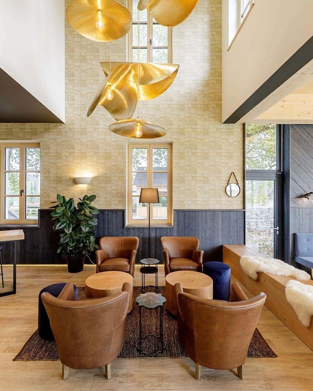 A cluster of Clérachic pendants hangs in a tall stairwell lined with patterned wallpaper.