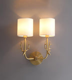 Brass deer head wall light glowing softly with white linen diffusers