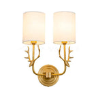 Sculptural brass antler wall light holding twin linen lampshades