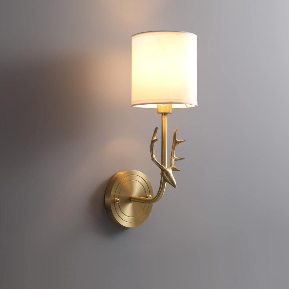 Brass antler wall light with warm linen-diffused glow on a wall