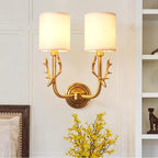 Brass antlered sconce with two white linen shades mounted on wall