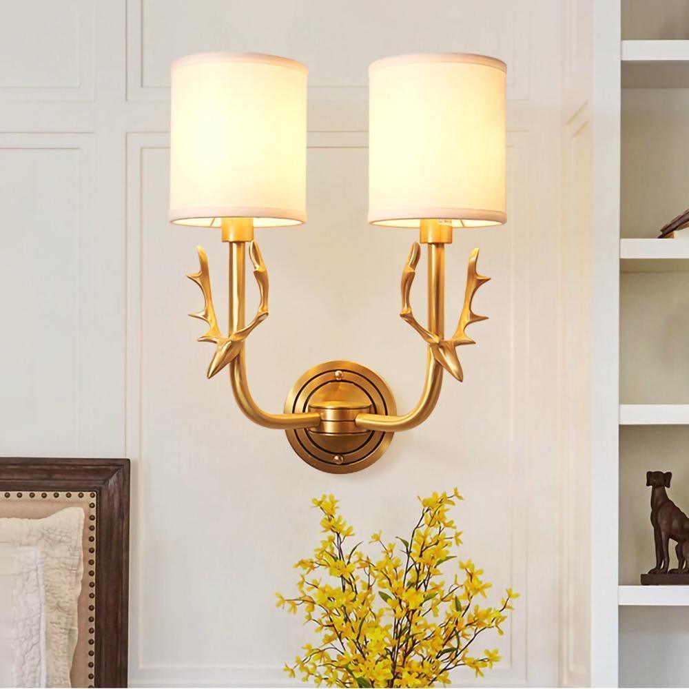 Brass antlered sconce with two white linen shades mounted on wall