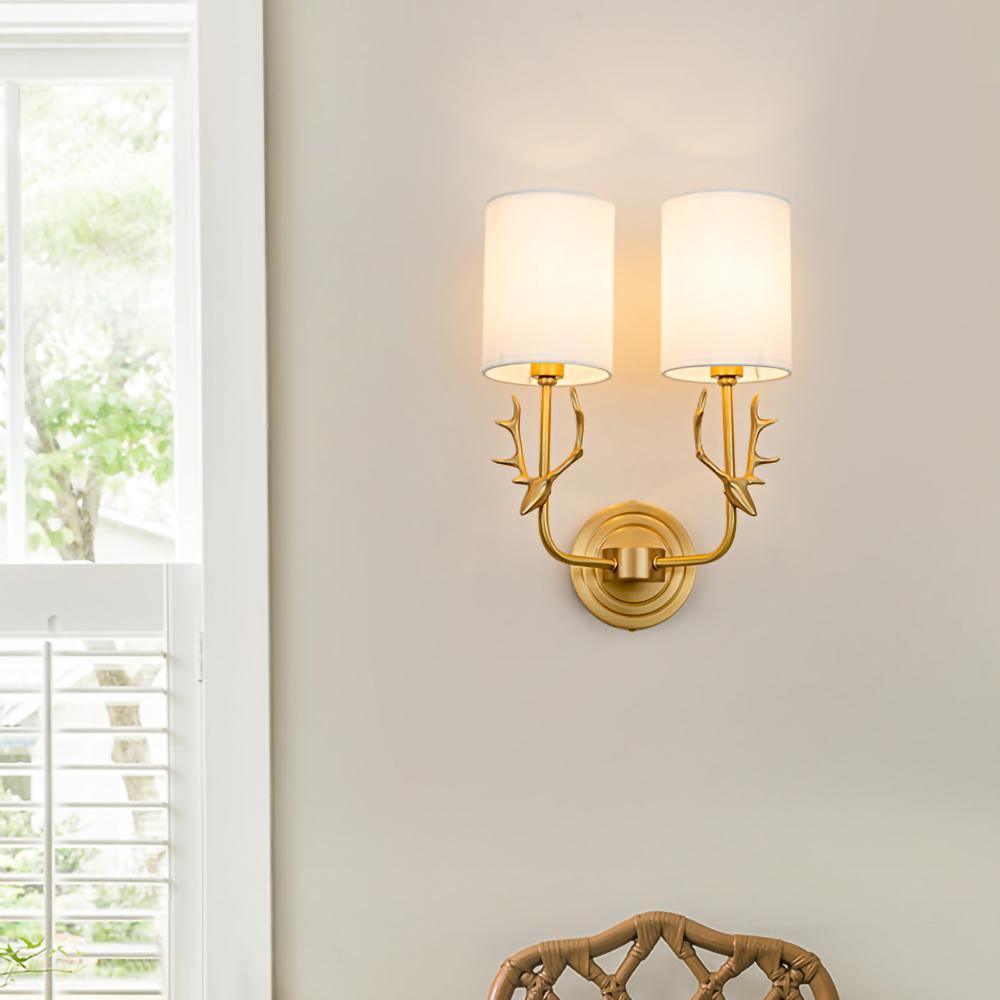 Brass deer head wall light with two white linen shades on a wall