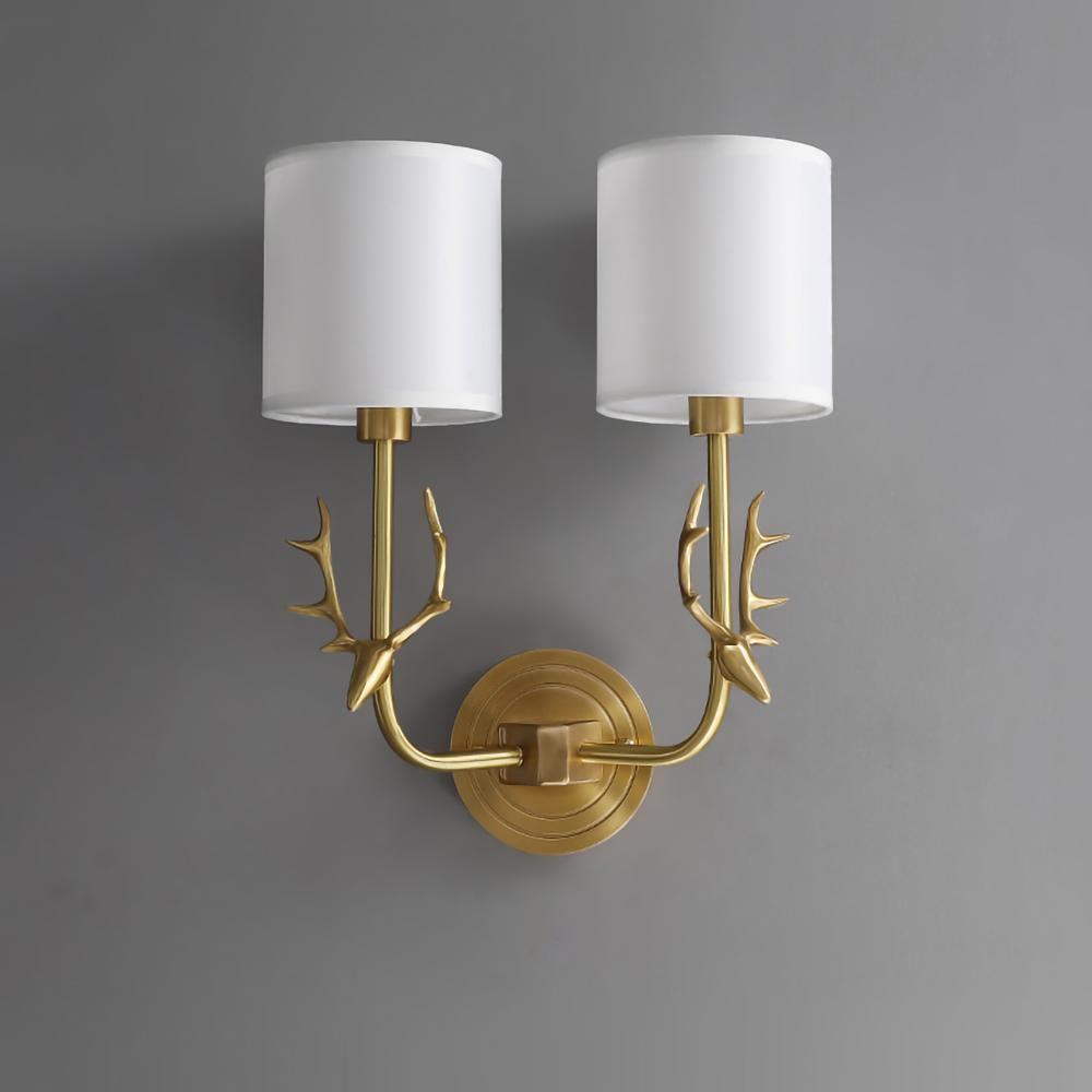 Brass antler sconce with two warm linen shades against a wall