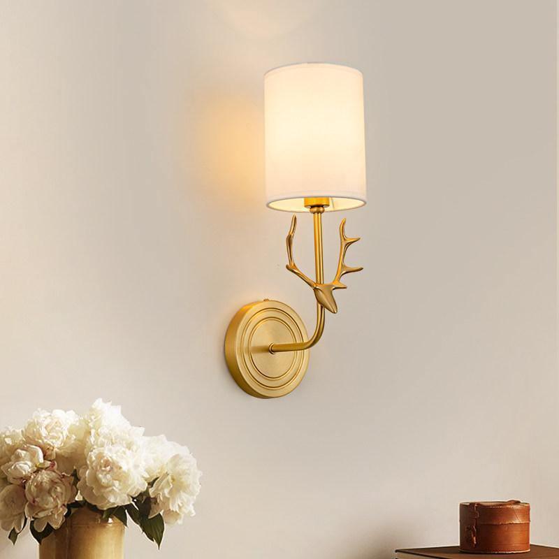 Brass antlered wall light with two warm linen shades lit