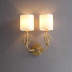Brass antler wall light casting a warm glow through linen shades