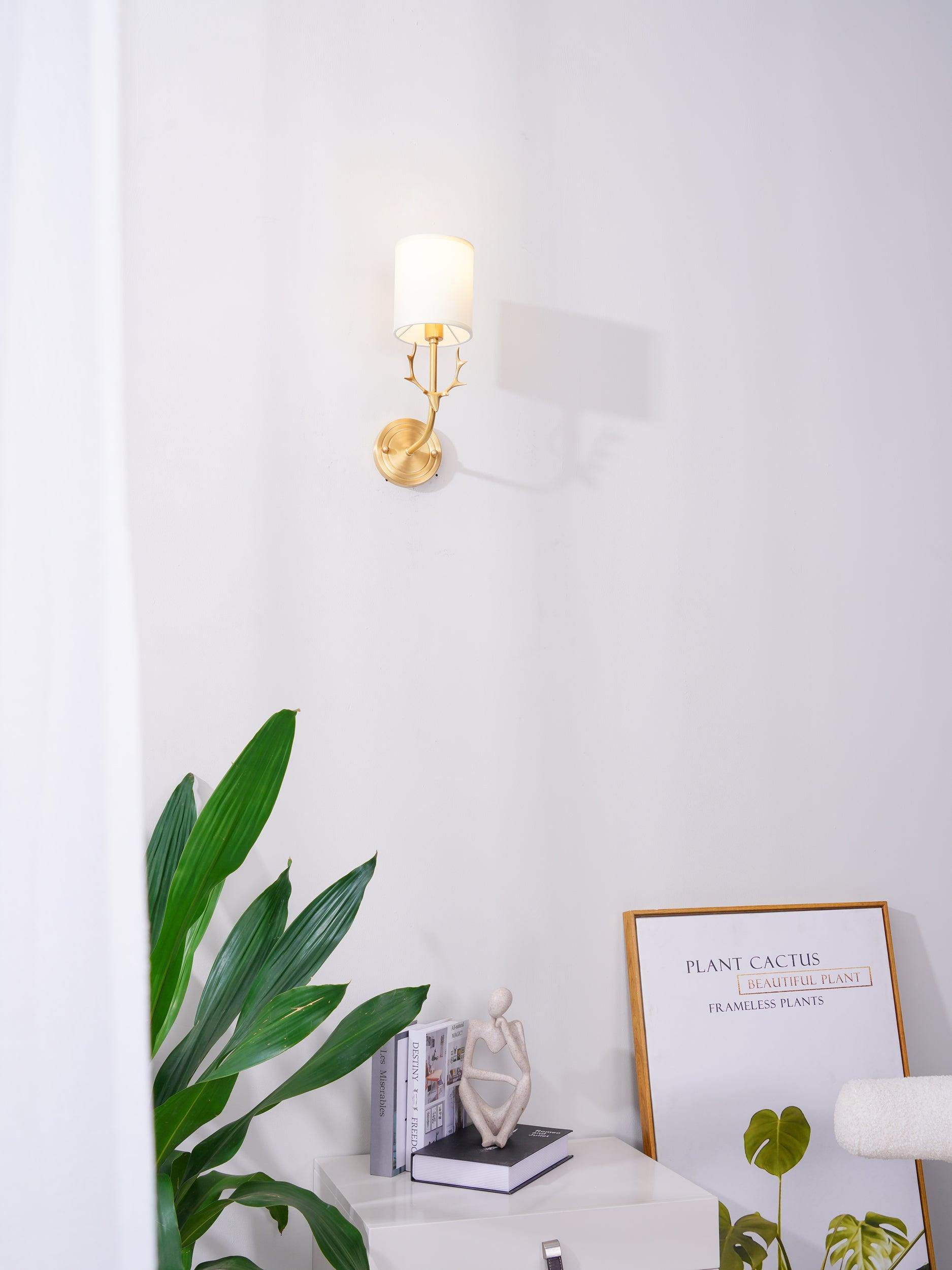 Brass deer head sconce with twin white linen shades glowing