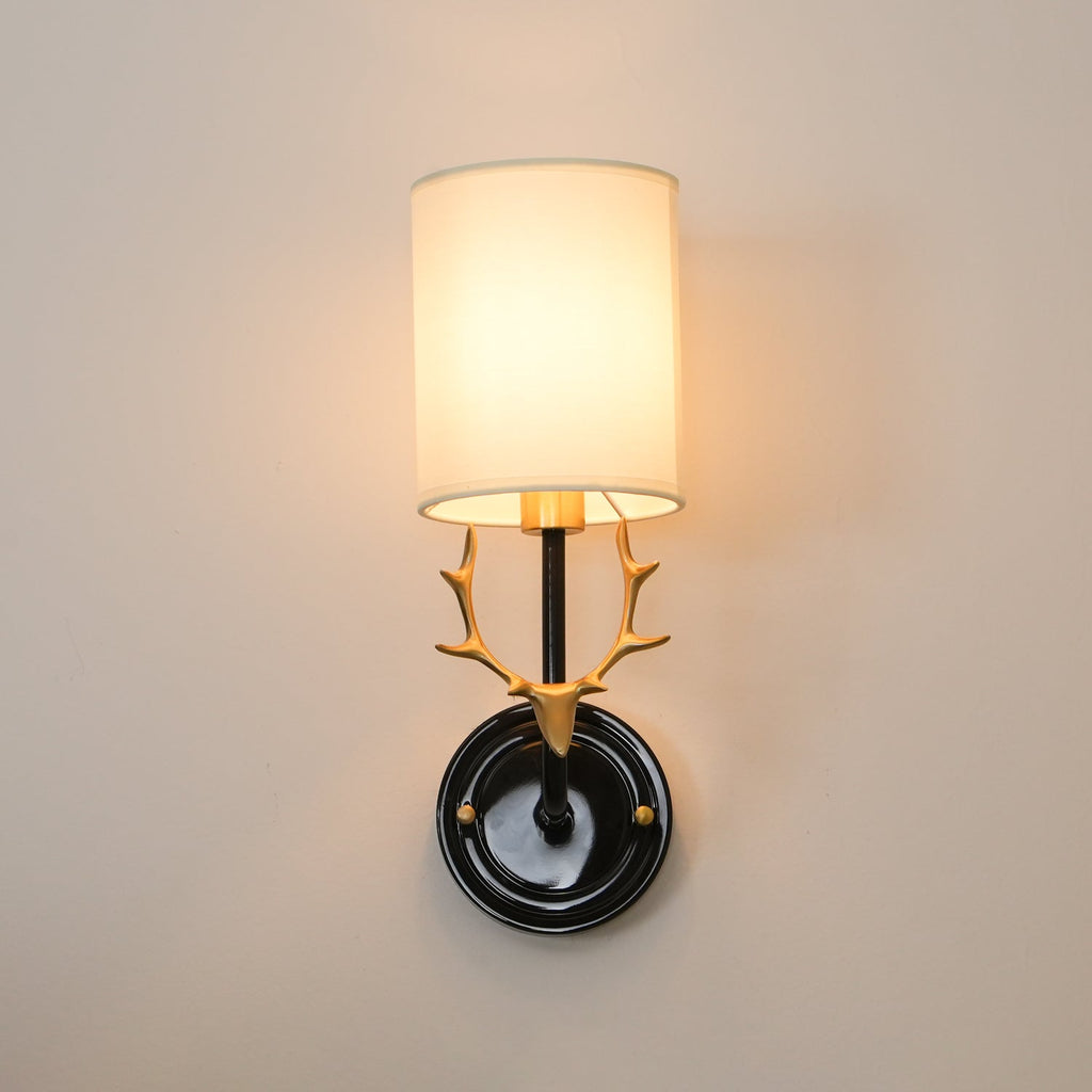Brass antler wall light with two warm glowing linen lampshades