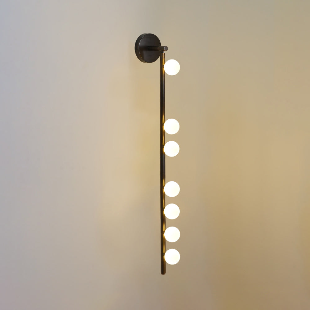 Brass glass tube wall lamp glowing warmly against a wall