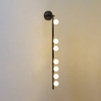 Brass glass tube wall lamp glowing warmly against a wall