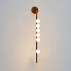 Glass tube wall lamp showing brass arms and warm globe light