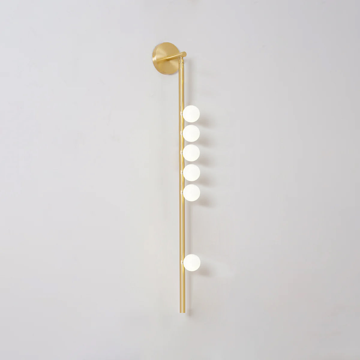 Brass glass tube wall lamp glowing softly in an intimate setting