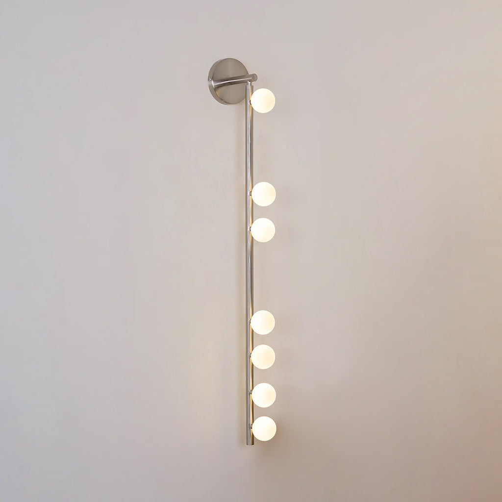 Nickel glass tube wall lamp with a row of softly lit globes