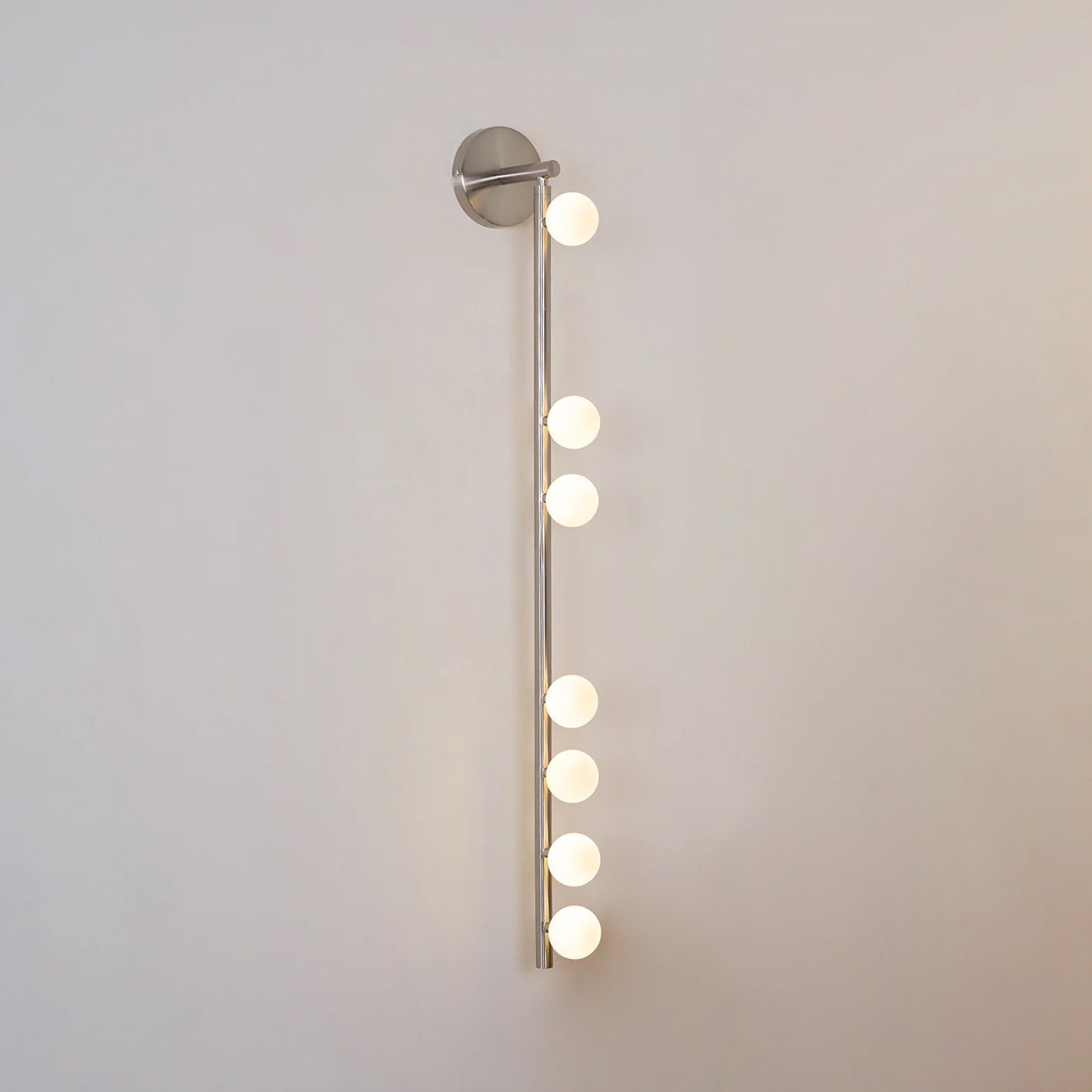 Nickel glass tube wall lamp with a row of softly lit globes