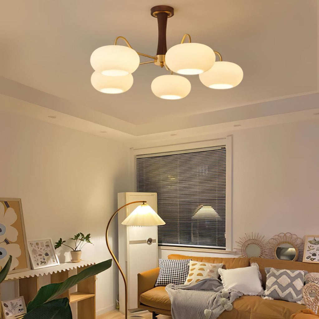 Persimmon chandelier with brass arms glowing in a bedroom