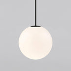 Opal glass globe pendant with brass rod over a nightstand