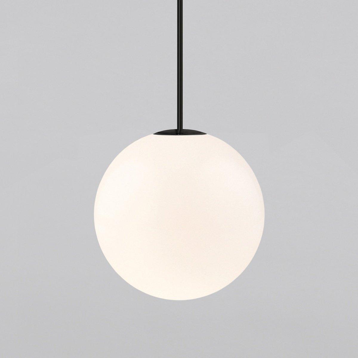 Opal glass globe pendant with brass rod over a nightstand