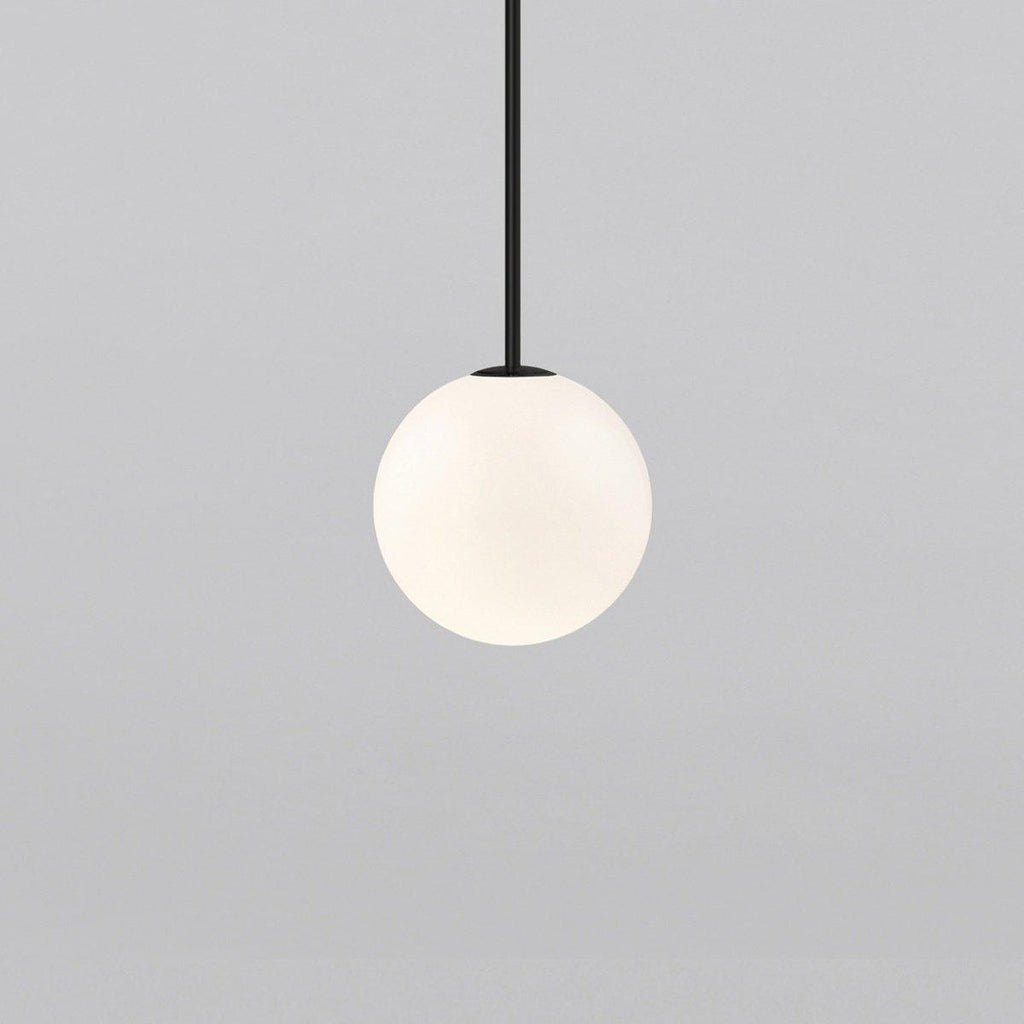 Opal glass globe pendant glowing warmly on a brass rod