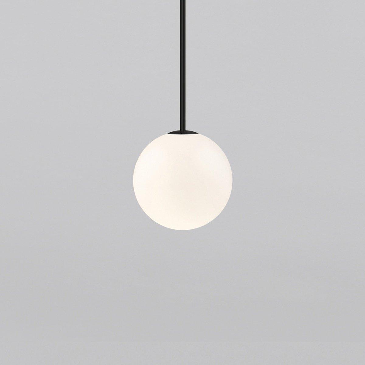 Opal glass globe pendant glowing warmly on a brass rod
