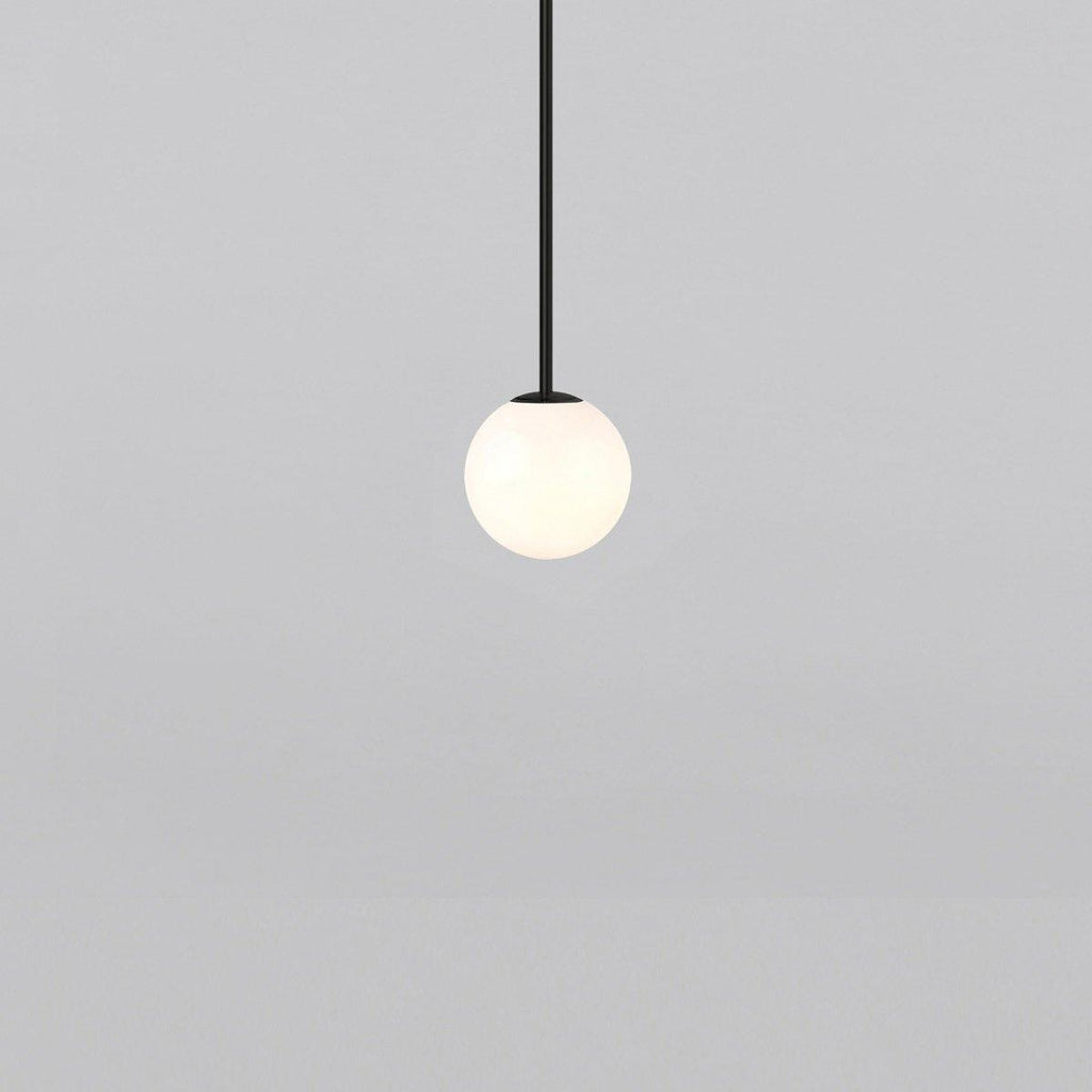 Opal glass globe pendant light suspended on a minimal brass rod