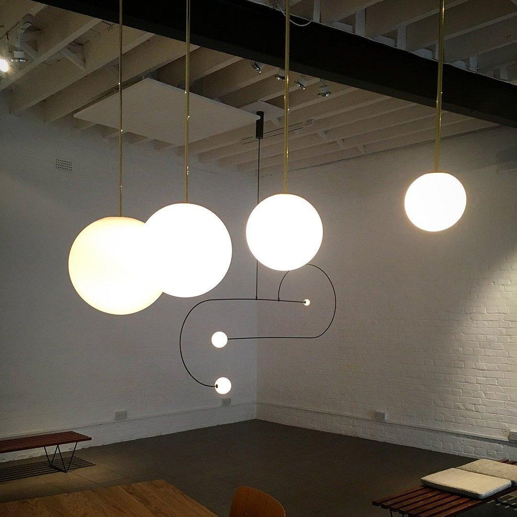 Brass rod globe pendant with white opal glass shade lit