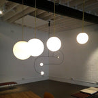 Brass rod globe pendant with white opal glass shade lit