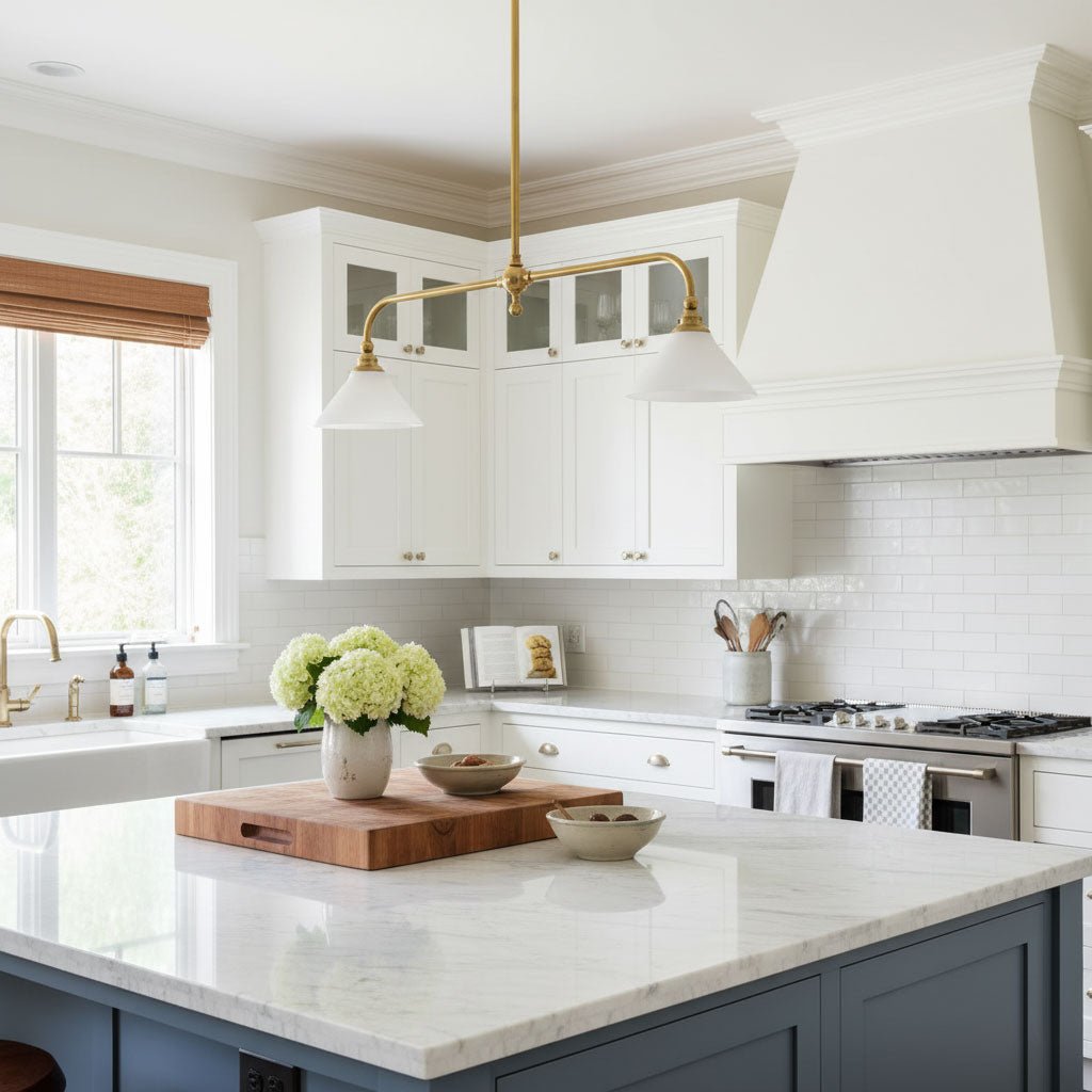 Navy cabinetry frames this Clérachic pendant, glowing warm above a marble island with a cutting board and flowers.