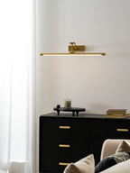 Gold wall light with warm glow over a piece of wall art